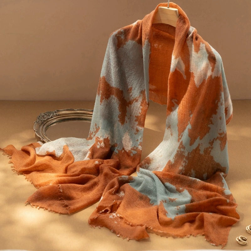 Luxury cashmere scarf in tangerine with a vibrant abstract tie-dye design, adding a pop of color.