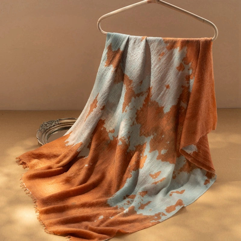 Close-up of the tangerine cashmere scarf, highlighting its bold and artistic pattern.