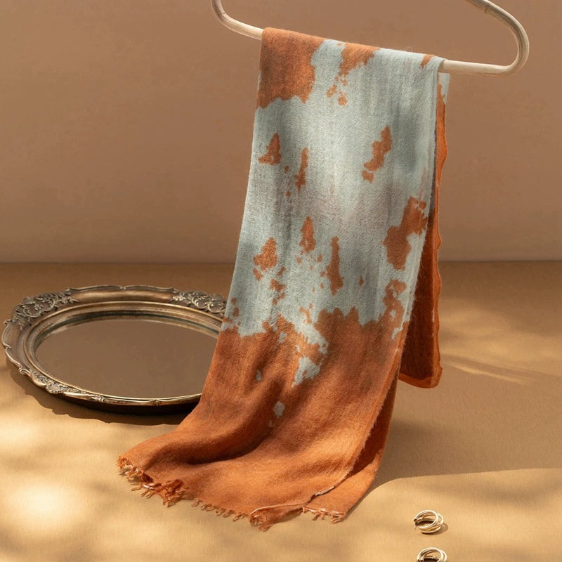 Tangerine cashmere scarf draped elegantly, emphasizing its lightweight and oversized dimensions.