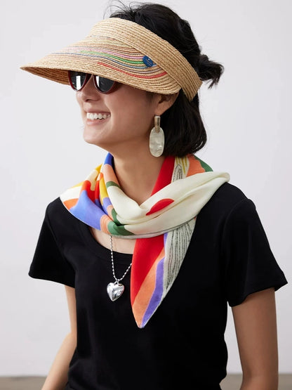 Woman styling an abstract art mulberry silk scarf around the neck with colorful sunset mountain pattern