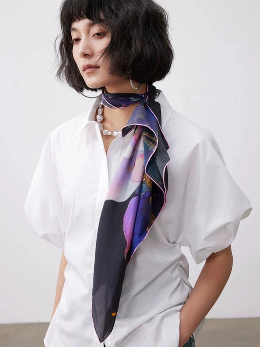 Artistic floral silk scarf styled around the neck, adding elegant color to a modern casual outfit