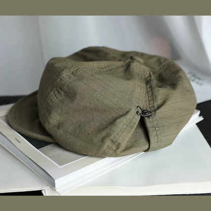 Bean green slouchy cotton beret hat with elastic adjustable fit, shown on a book for casual everyday styling