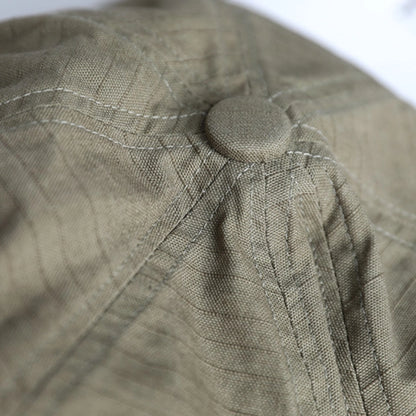 Close-up of bean green slouchy cotton beret showing soft cotton texture, stitched panels, and gathered top detail
