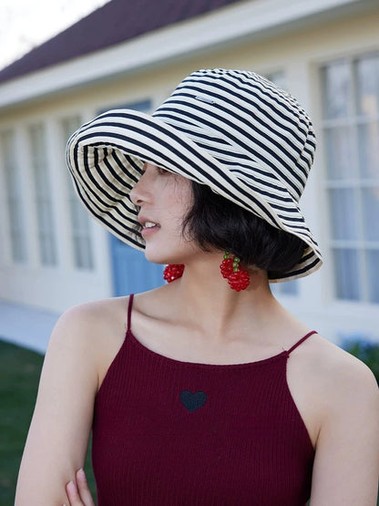 Side view of a beige and black striped wide brim sun hat styled with a summer outfit.
