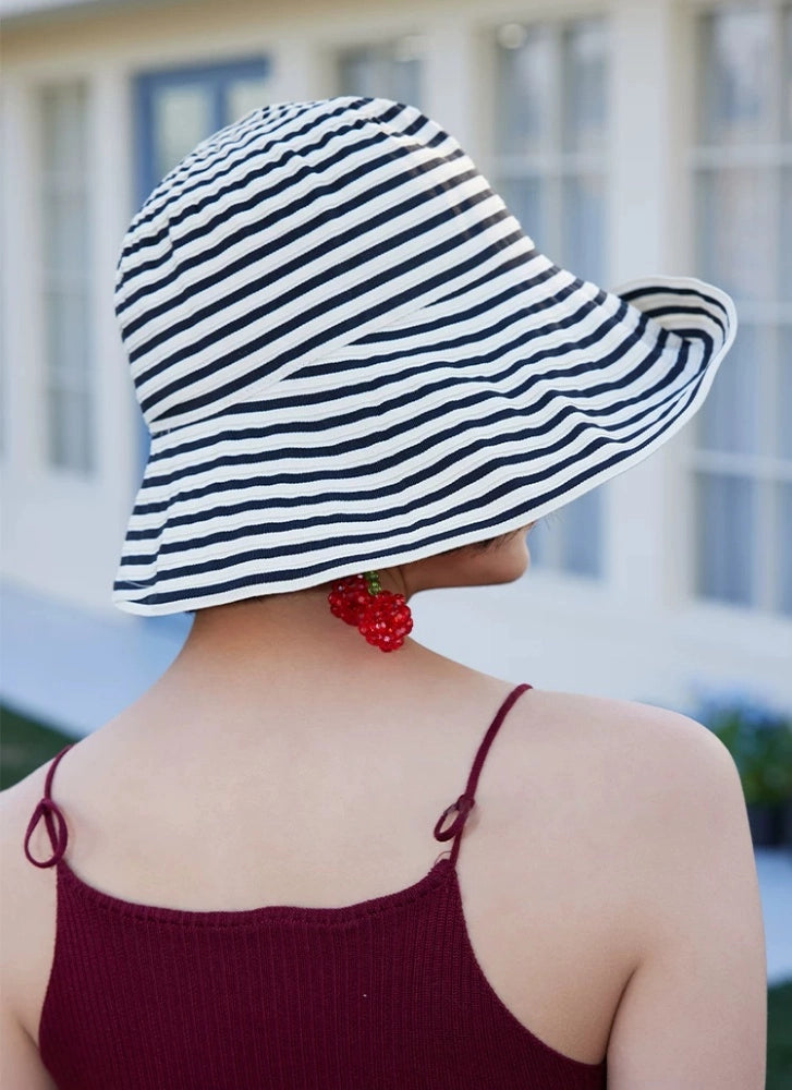 Back view of a beige and black striped summer beach hat with a flexible wavy brim.