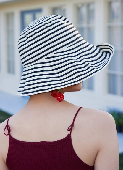 Back view of a beige and black striped summer beach hat with a flexible wavy brim.