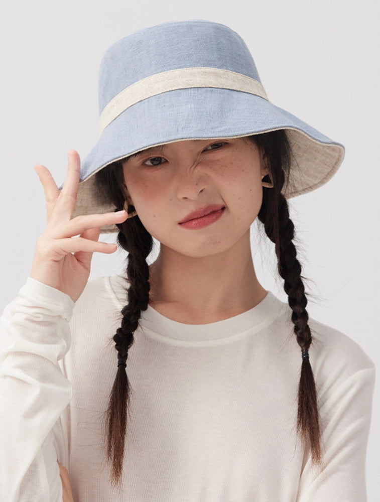 Model wearing a beige blue reversible ramie cotton bucket hat with a wide brim