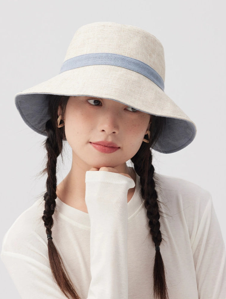Model wearing the beige side of a reversible bucket hat with blue contrast trim