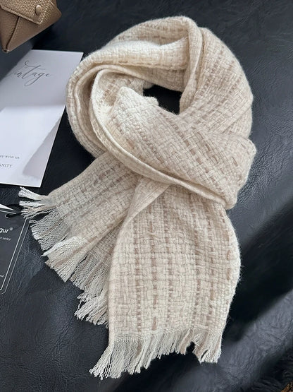 Beige cashmere tweed scarf loosely looped on a dark chair, showing its checked weave and fringed ends.