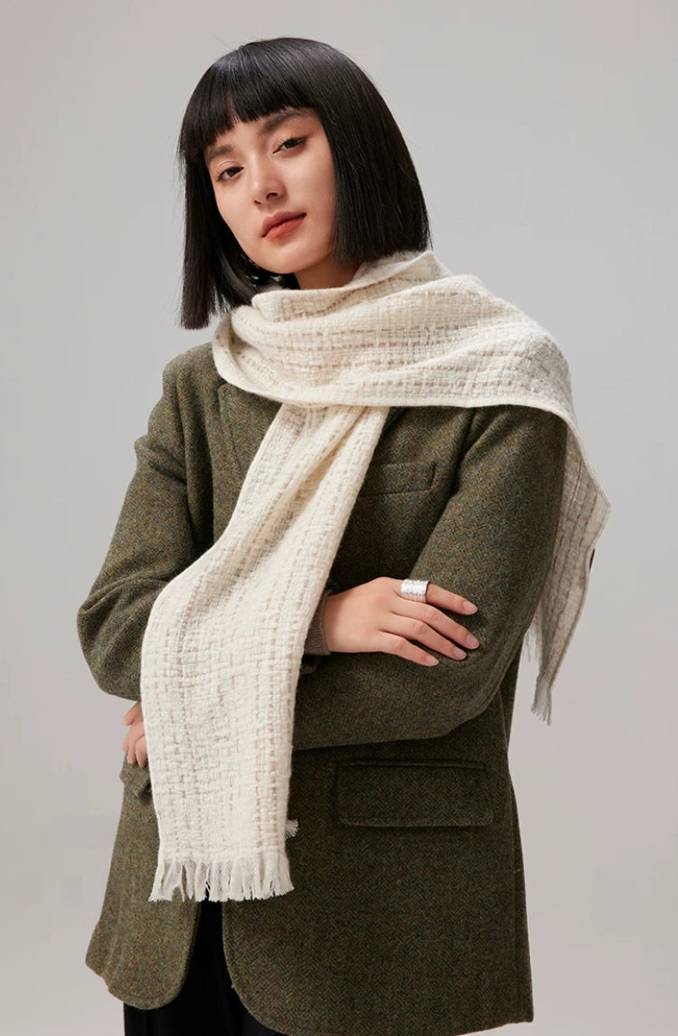 Front view of a beige cashmere tweed scarf wrapped around a model's neck over an olive blazer.