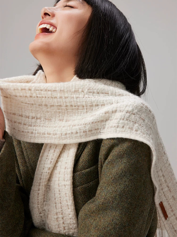 Close-up of a beige cashmere tweed scarf wrapped around the neck, showing its textured check weave.