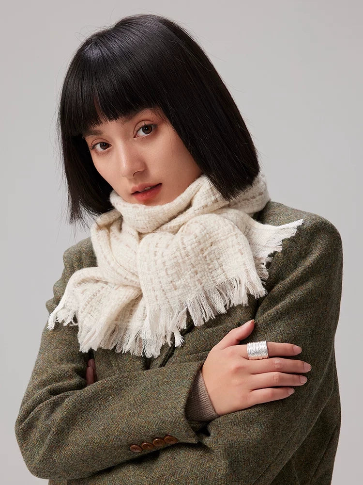 Beige cashmere tweed scarf wrapped snugly around a model's neck, with fringed ends over an olive blazer.
