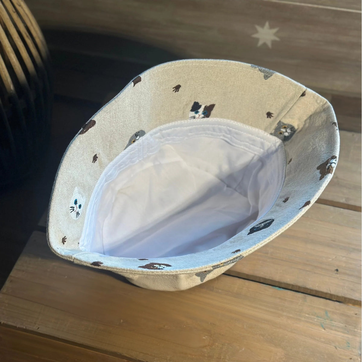 Interior view of a beige cotton cat bucket hat showing its white lining