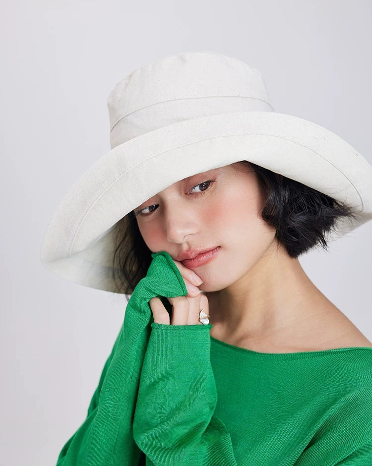 Front view of a beige linen cotton wide brim sun hat styled with a green summer top.