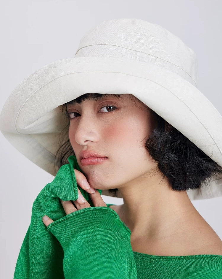 Side view of a beige linen blend sun hat with a wide wrap-around brim for added shade.
