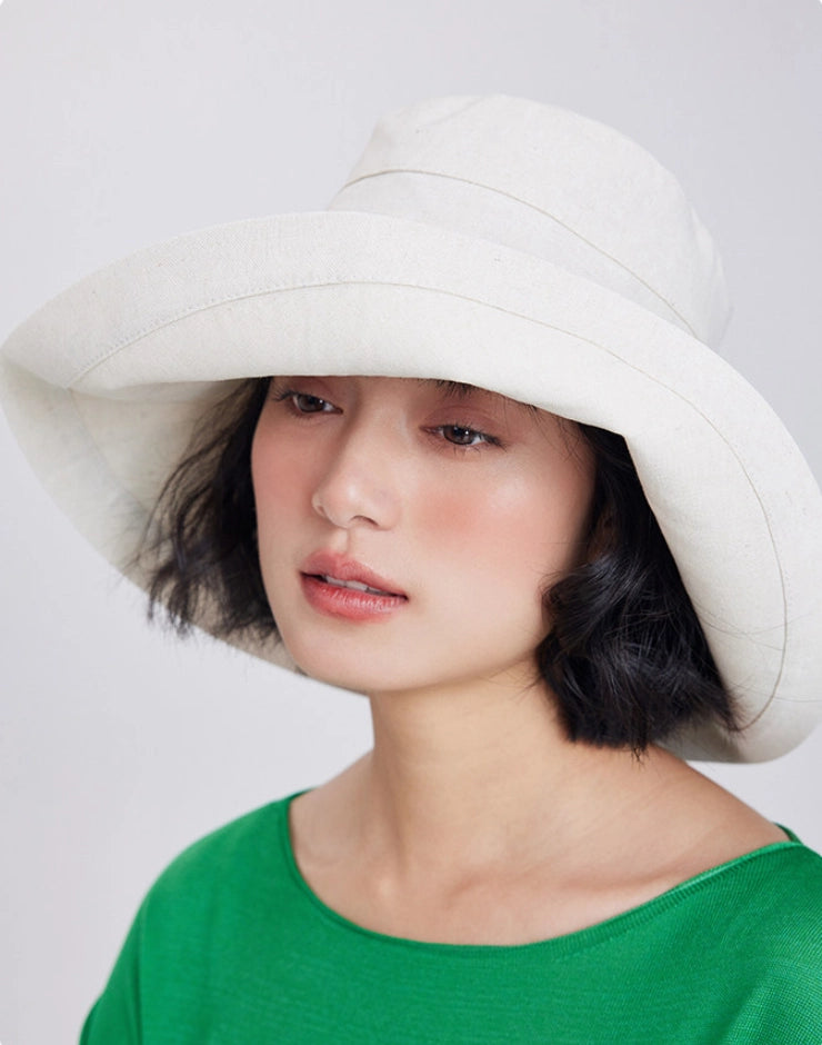 Woman wearing a beige adjustable wide brim sun hat for beach, travel, and summer outings.
