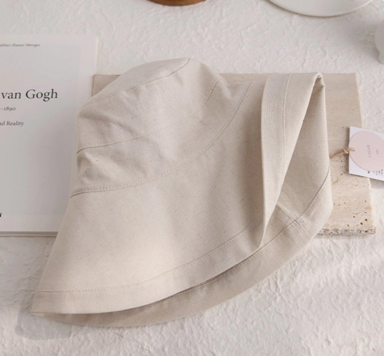 Close-up of beige linen cotton sun hat showing the foldable brim and natural fabric texture.