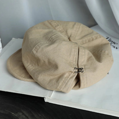 Beige cotton beret hat displayed on a book, featuring a breathable fabric and casual slouchy silhouette