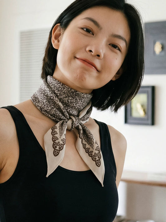 Woman styling a beige silk wool neck scarf with a black sleeveless top and front knot