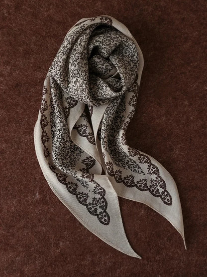 Beige vintage floral silk wool scarf arranged on a brown textured background
