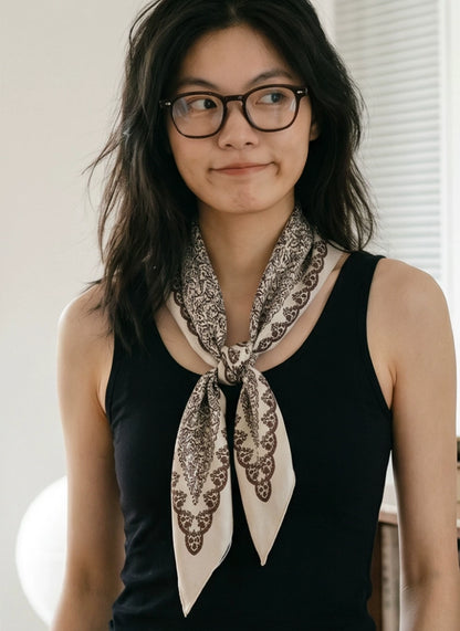 Beige floral triangle scarf tied loosely at the neck with long pointed ends over a black top