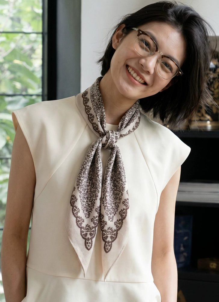 Woman wearing a beige vintage floral silk wool neckerchief with an ivory sleeveless blouse