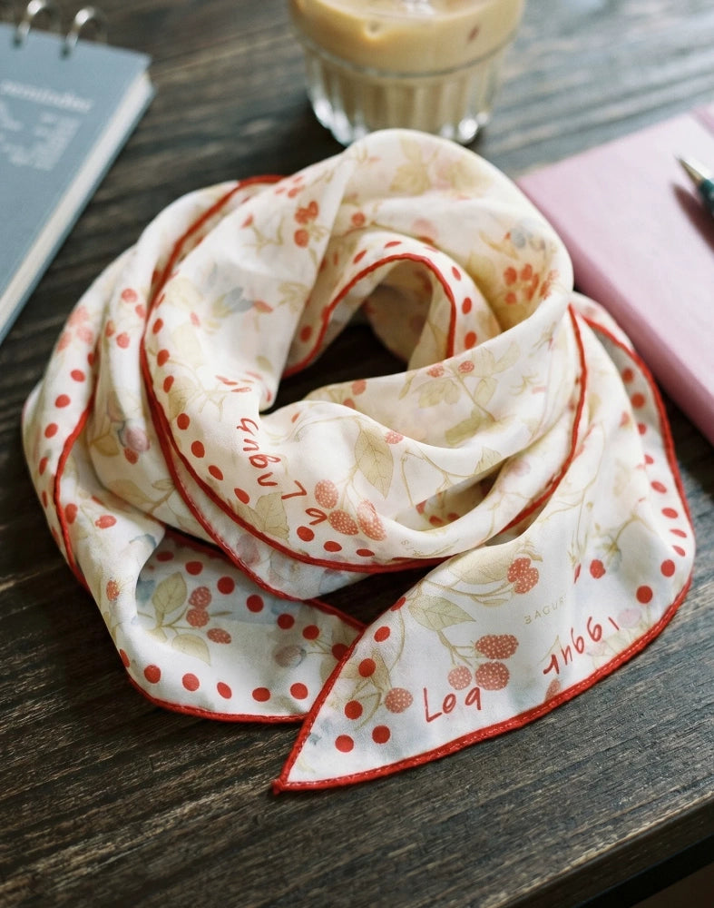 Berry rabbit print silk skinny scarf loosely looped on a wooden table