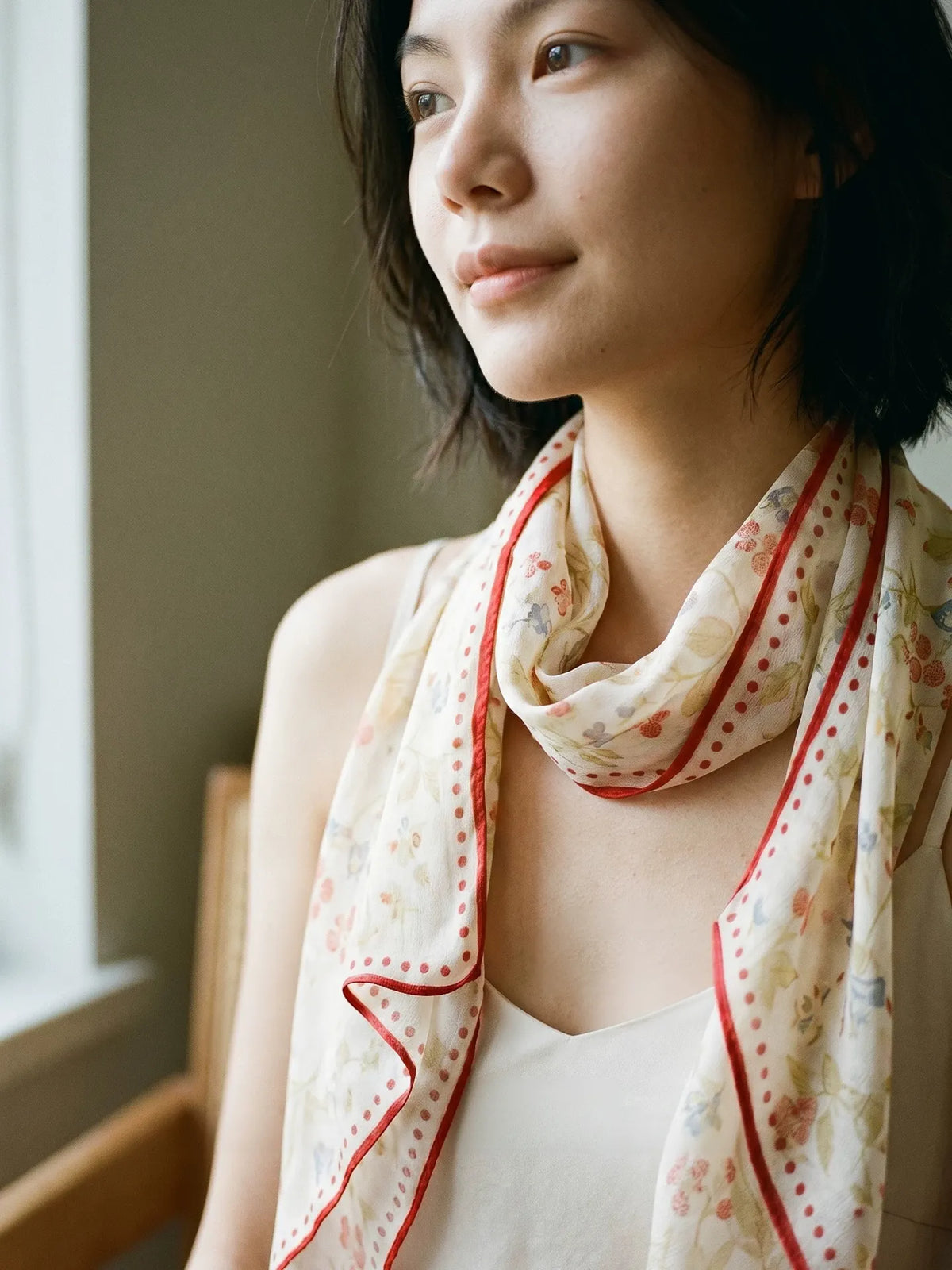Woman wearing a berry rabbit print mulberry silk scarf wrapped around the neck