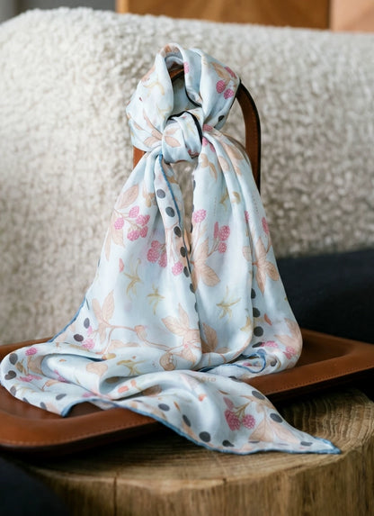 Long sky blue berry rabbit print mulberry silk scarf knotted over a textured chair