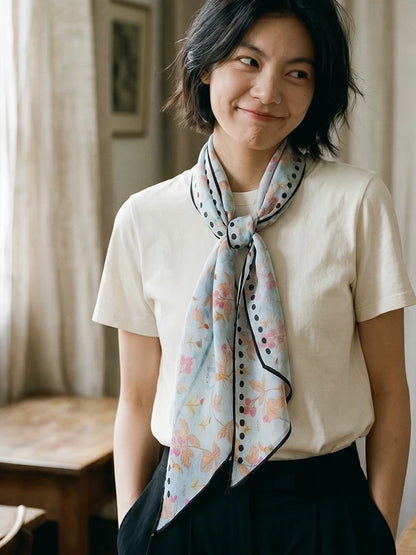 Woman wearing a sky blue berry rabbit print silk scarf in a long necktie style