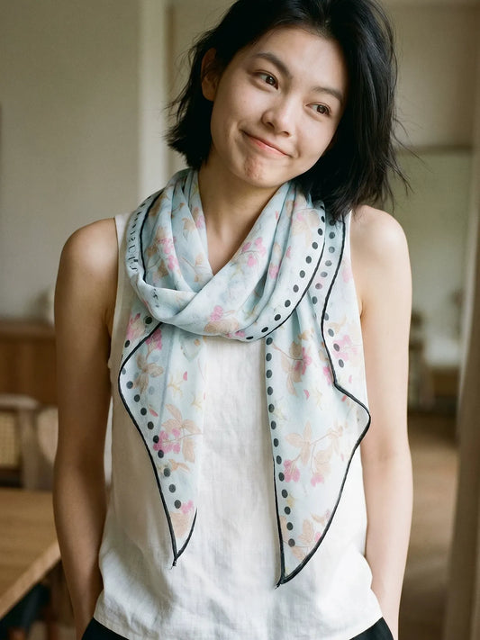 Woman styling a sky blue mulberry silk skinny scarf in a relaxed loop over a white top