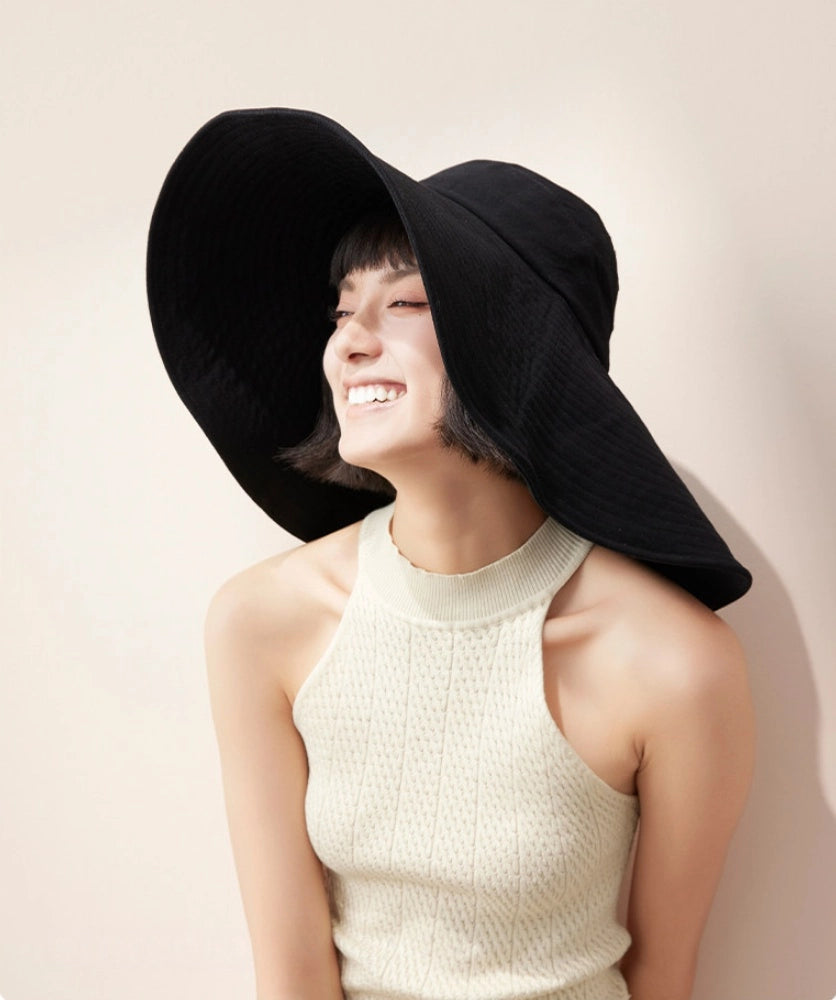 Woman styling black oversized cotton sun hat with wide brim and adjustable wind cord