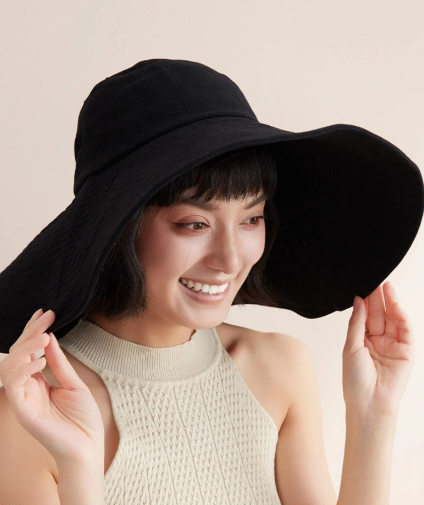 Smiling woman wearing black cotton oversized sun hat with wind cord for beach and travel