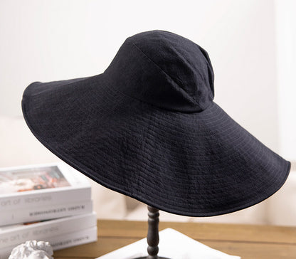Black cotton wide brim sun hat displayed on table with soft foldable brim and wind cord
