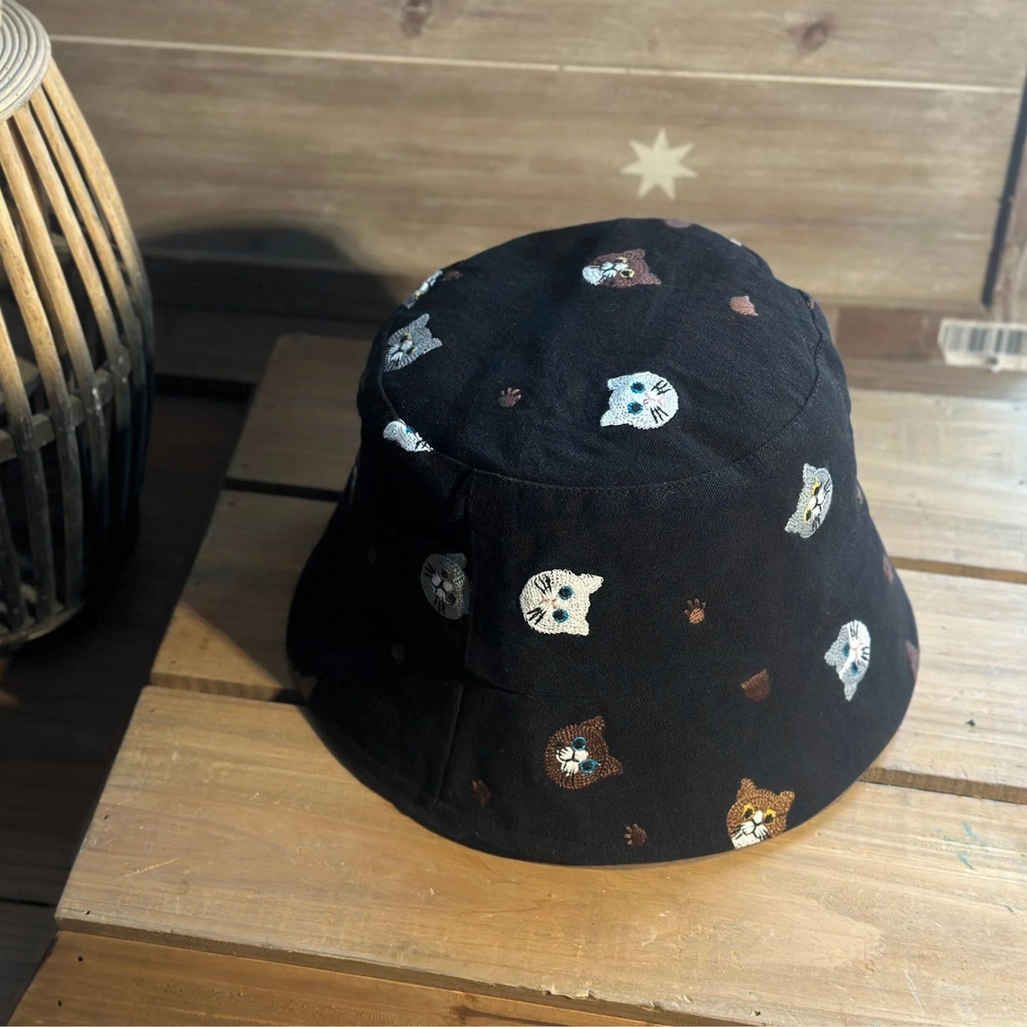 Three-quarter view of a black embroidered cat bucket hat showing the all-over pattern