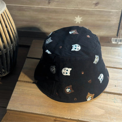 Three-quarter view of a black embroidered cat bucket hat showing the all-over pattern