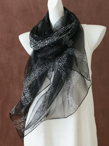 Lightweight black floral silk scarf draped around a mannequin to show its translucent finish