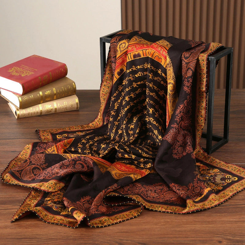 Black gold Xiangyun silk scarf draped beside vintage books to display its large square shape