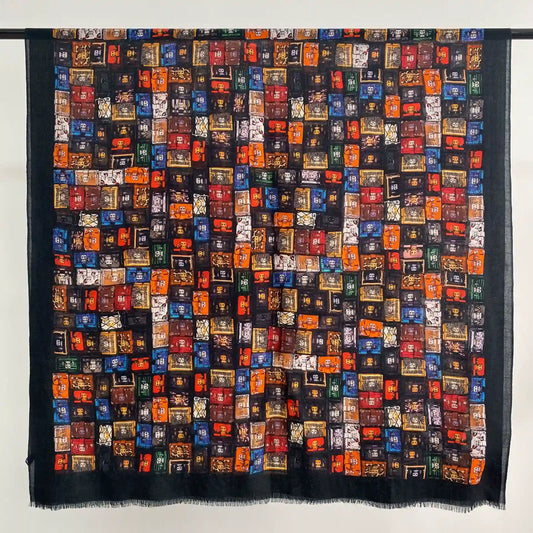 Black fine wool scarf laid flat with a colorful vintage trunk graffiti print and softly fringed edges