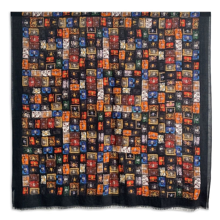 Full view of a black fine wool scarf featuring a multicolor vintage trunk print in red, orange, blue and green