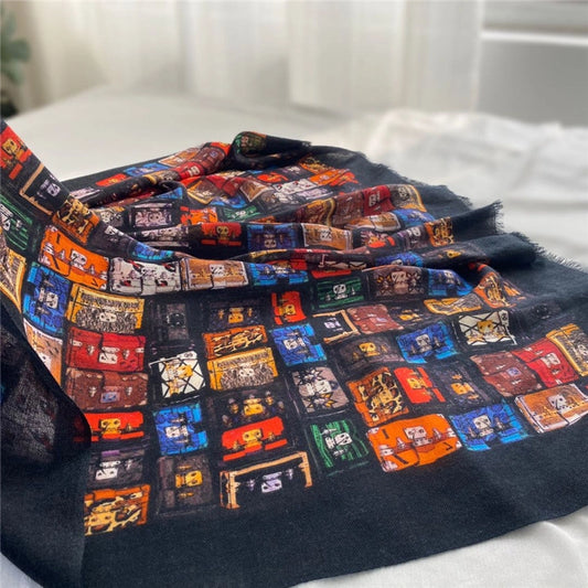 Close-up of a draped black fine wool scarf showing the colorful trunk-inspired print and soft woven texture