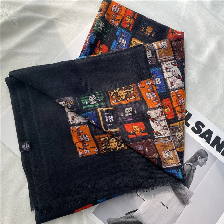Folded black fine wool scarf showing its solid black reverse and colorful vintage trunk print on white fabric