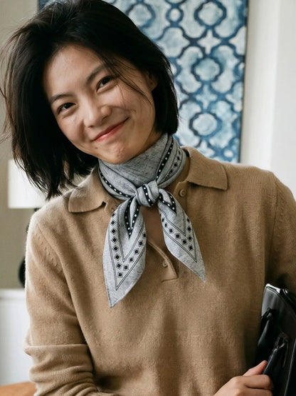 Model wearing a black and gray geometric silk wool scarf with a camel sweater
