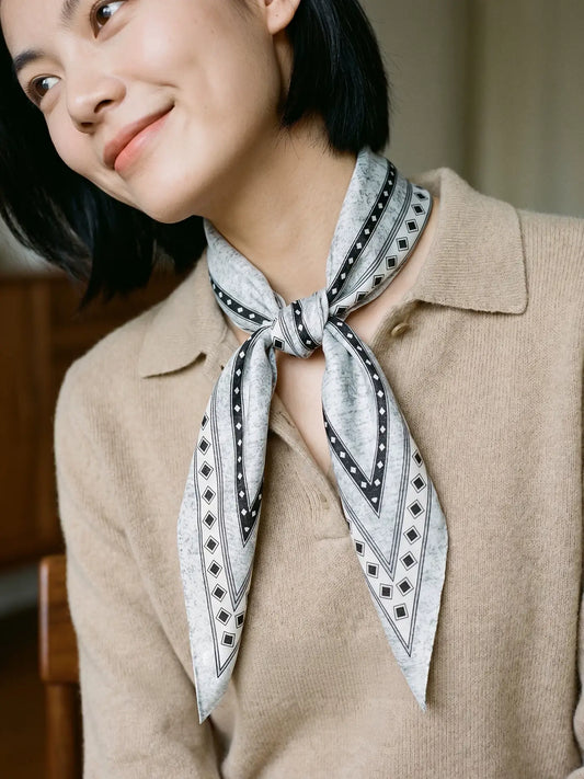 Close view of a black and gray diamond print silk wool scarf styled as a neckerchief