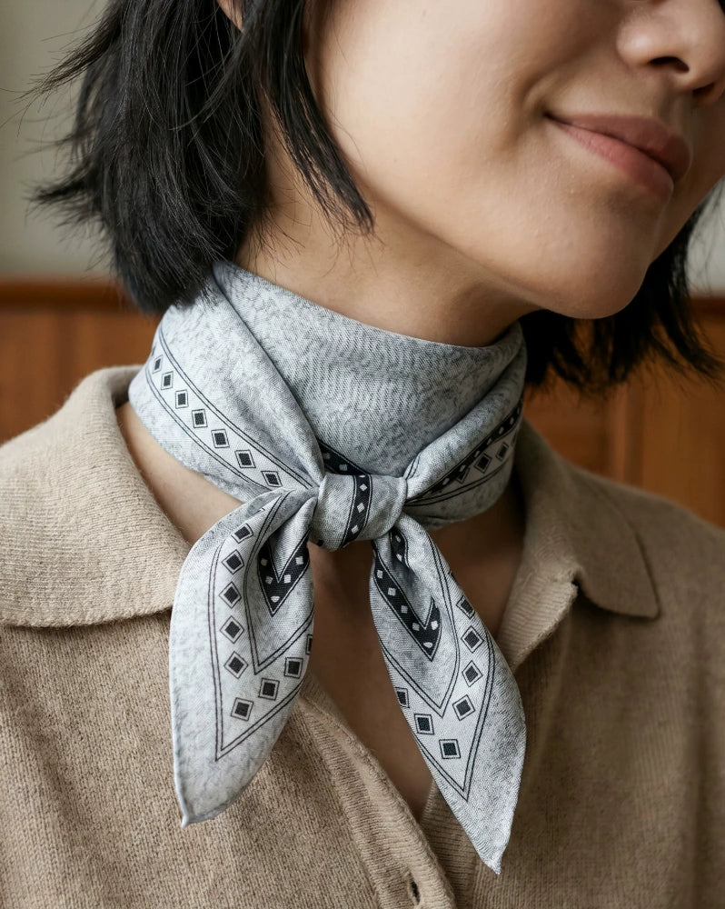 Close-up of a black and gray diamond print silk wool scarf knotted at the neck