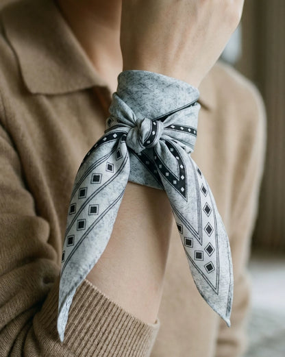 Black and gray geometric silk wool scarf tied in a bow around the wrist