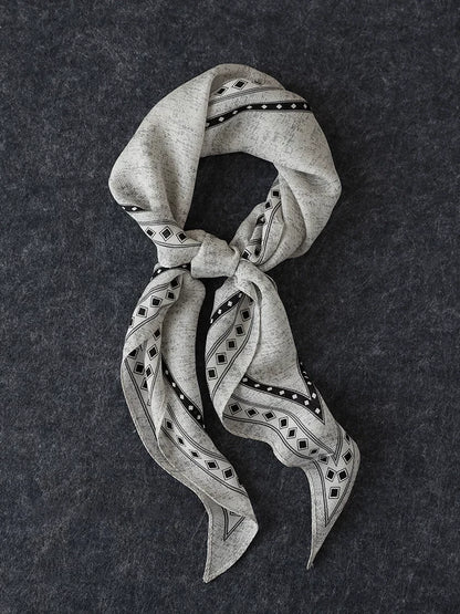 Black and gray silk wool diamond scarf loosely knotted on a dark textured surface