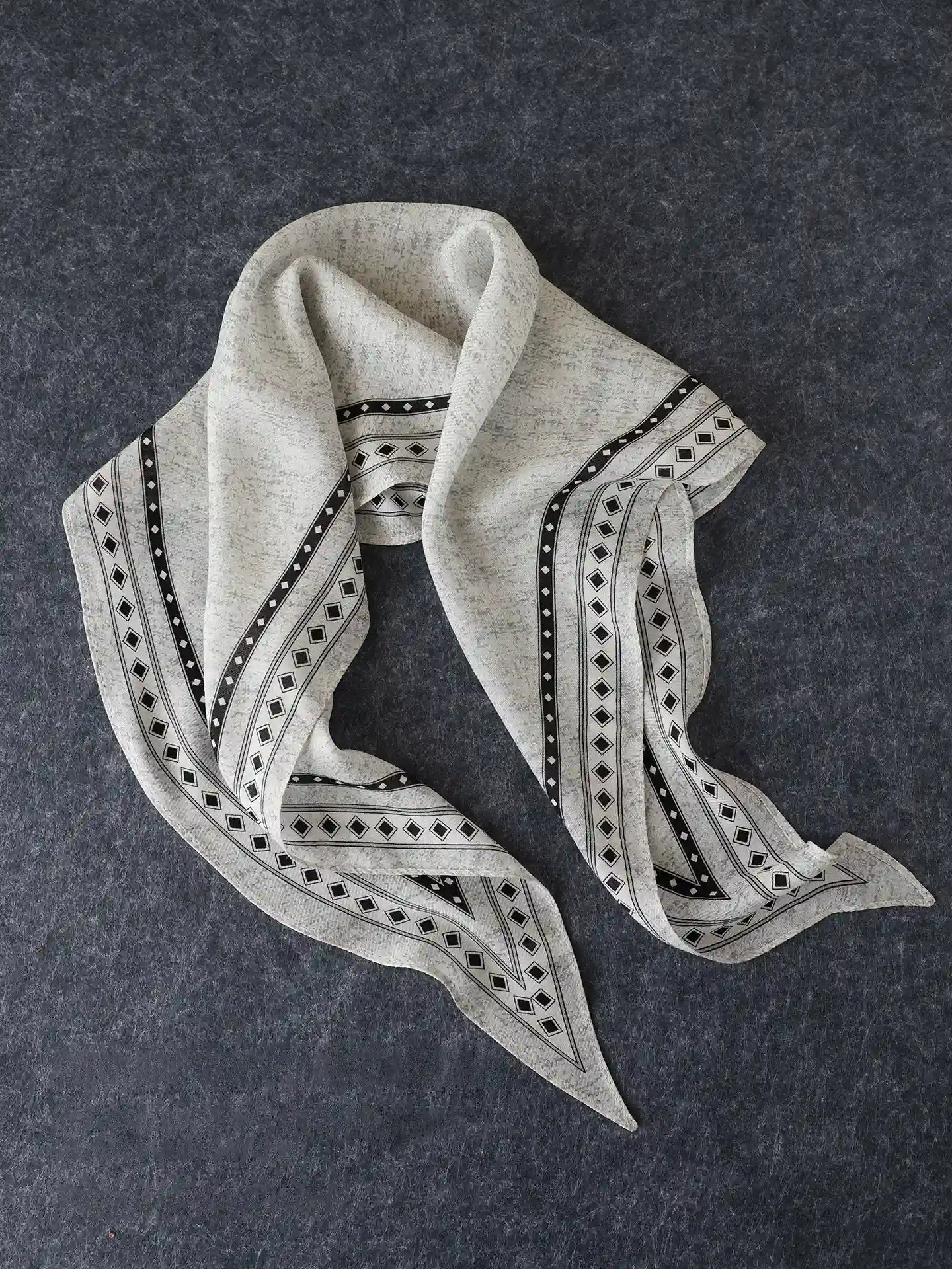 Black and gray geometric silk wool scarf arranged to show its tapered diamond shape