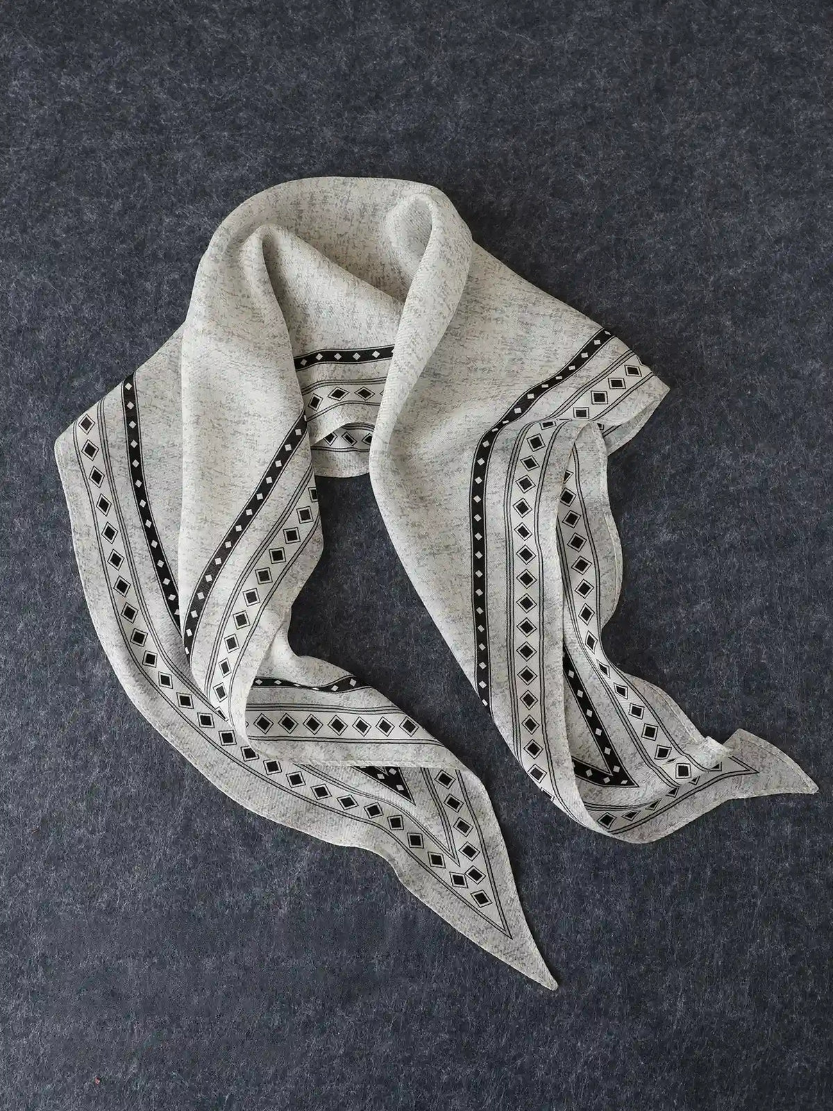 Black and gray geometric silk wool scarf arranged to show its tapered diamond shape