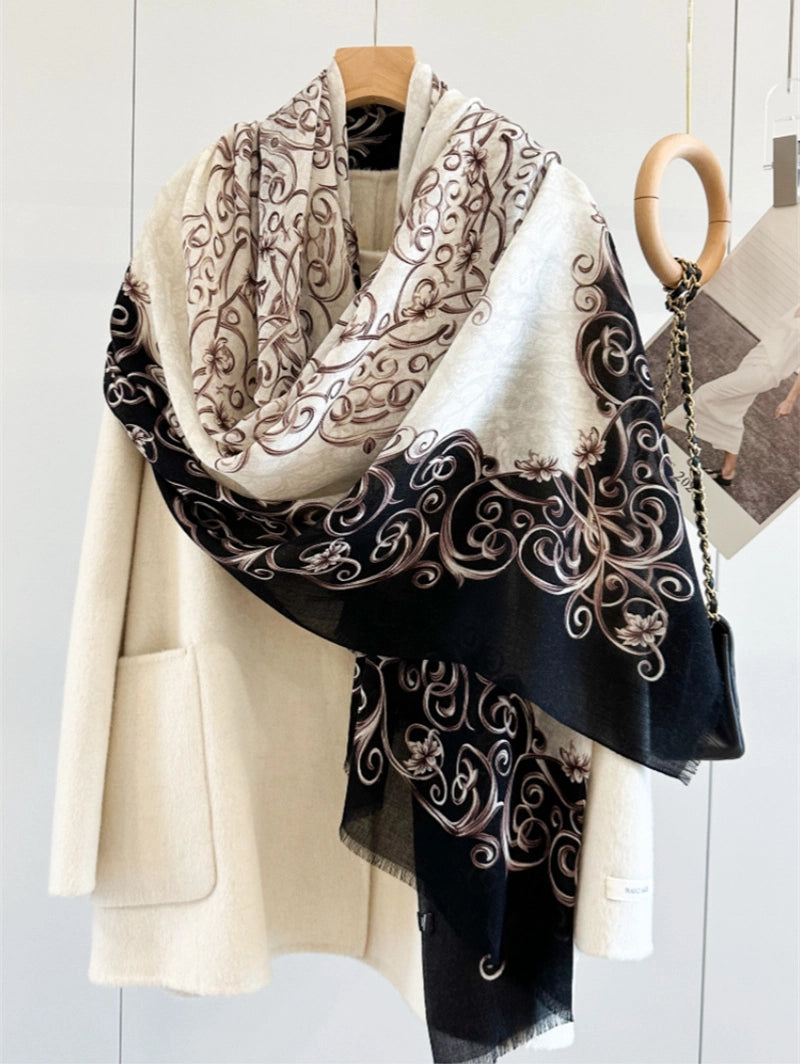 Ivory side of a black Baroque wool scarf wrapped softly around an ivory coat